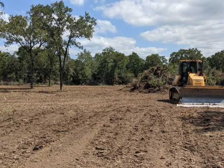 Yellow bulldozer clearing brush and vegetation from raw land