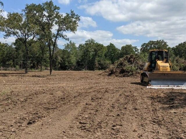 Yellow bulldozer clearing trees and brush from raw land